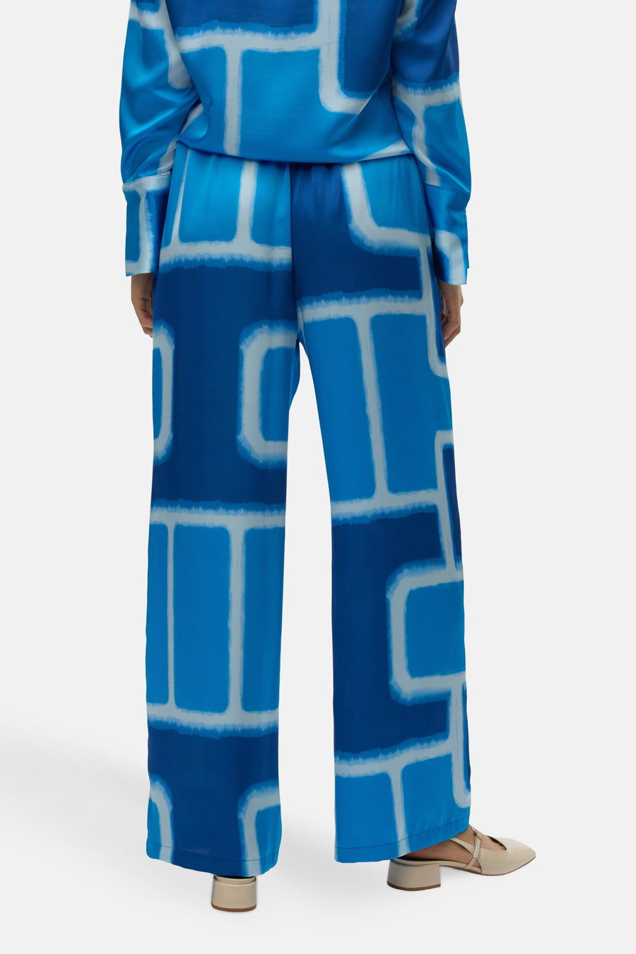 Blauwe broek met grafische print, van VERO MODA®, met rechte pasvorm en crèmekleurige schoenen.