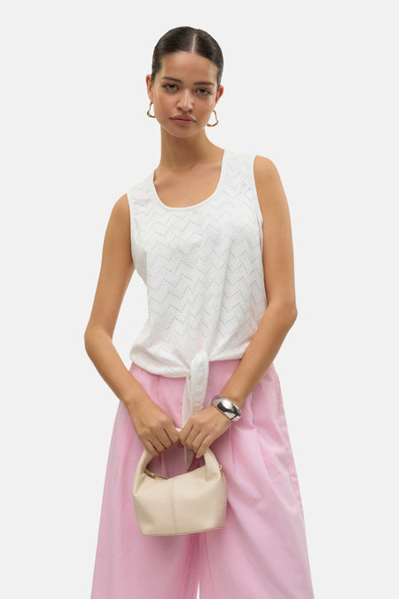 Wit mouwloos hemd van VERO MODA, ajour chevronpatroon, gestrikt op een roze broek en een zilveren armband.