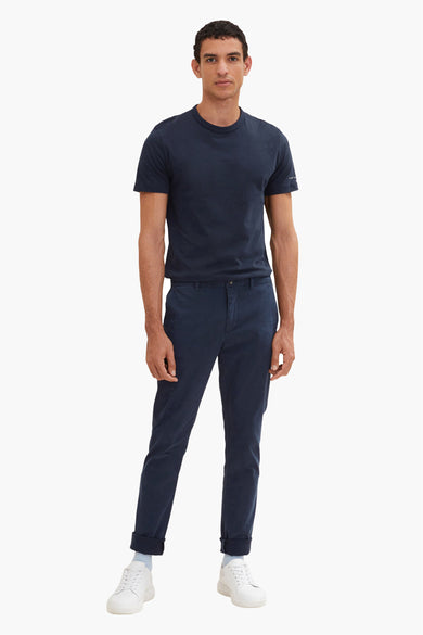 Chino bleu de Tom Tailor, porté avec un t-shirt bleu marine et des chaussures de sport blanches.