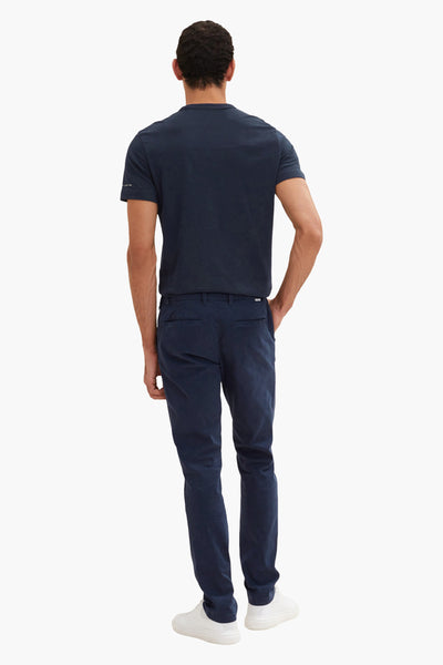 Blauwe chino van Tom Tailor, gedragen met een marineblauw T-shirt en witte schoenen, achterzicht.