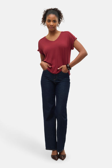 T-shirt rouge à manches courtes de Vero Moda, porté avec un jean et un bracelet en bois.