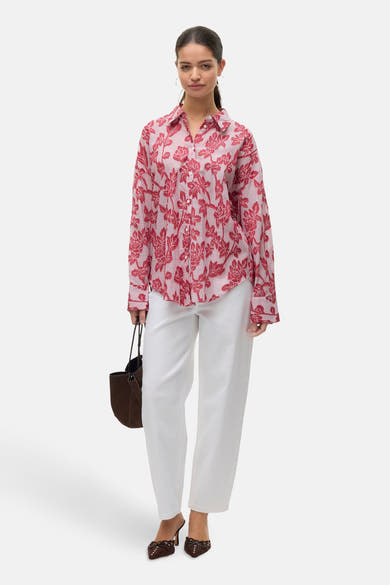 Chemise à manches longues rouge à rayures et motif floral, de VERO MODA, portée avec un pantalon blanc et un sac marron.