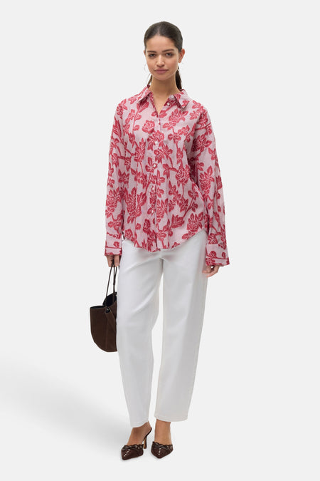 Chemise à manches longues rouge à rayures et motif floral, de VERO MODA, portée avec un pantalon blanc et un sac marron.