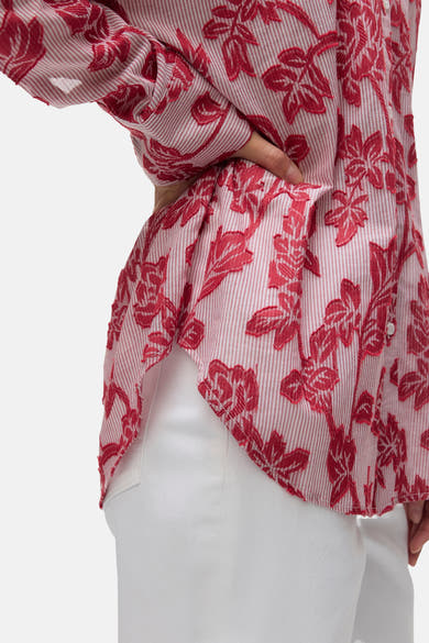 Rood gestreept overhemd met lange mouwen en bloemenprint van VERO MODA, gedragen met een witte broek, zijwaarts bekeken.