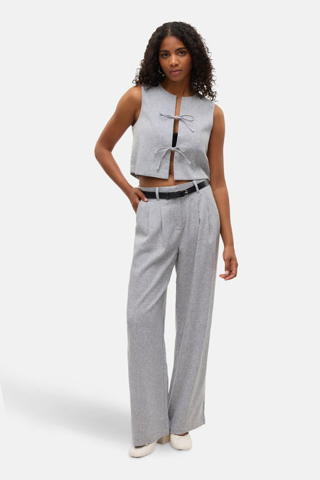 Grijze pantalon van VERO MODA, met zwarte riem, gedragen met een bijpassende top.