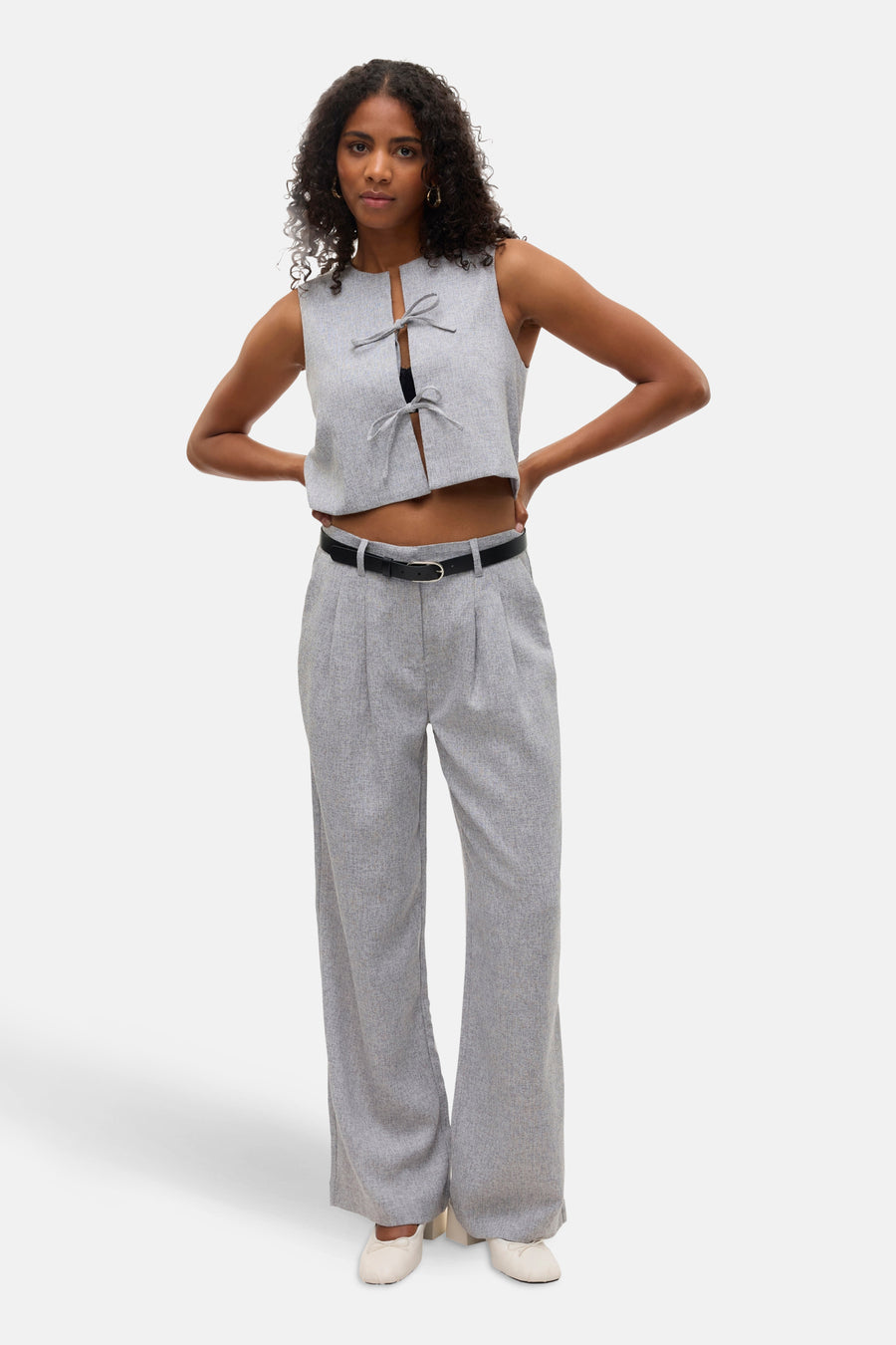 Pantalon de costume gris de VERO MODA, avec une ceinture noire, porté avec un top court assorti.