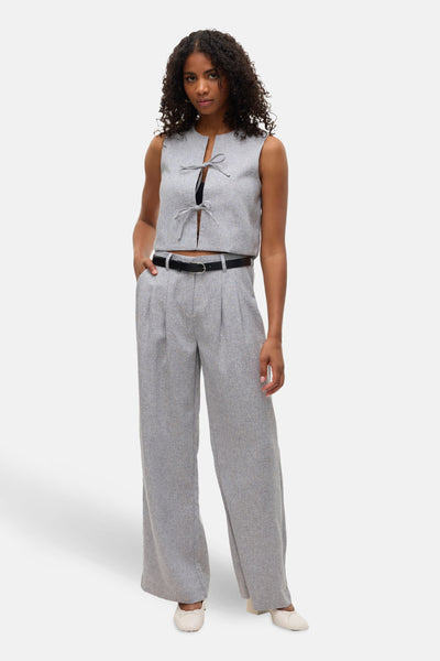 Grijze blouse met korte mouwen van VERO MODA®, met decoratieve strikjes en gedragen met een wijde broek en een zwarte riem.