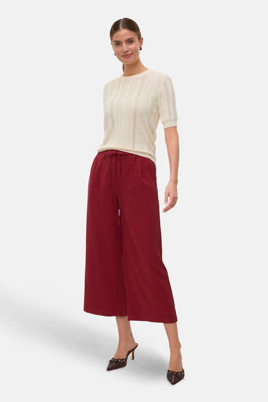 Rode broek van VERO MODA®, losse pasvorm met trekkoord, gedragen met een crèmekleurige top en bruine pumps.