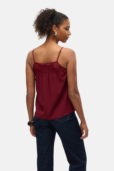 Chemisier bordeaux sans manches de VERO MODA, avec empiècement en dentelle au dos, porté avec un jean.
