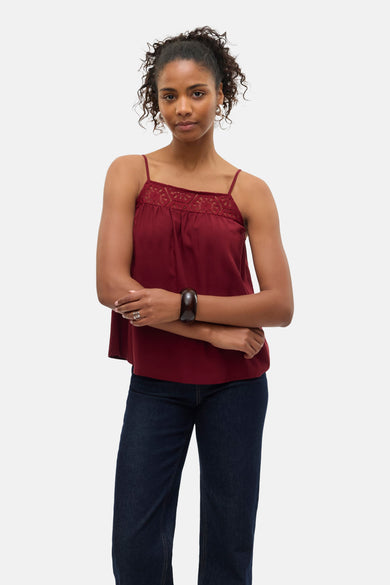 Blouse bordeaux sans manches de Vero Moda, avec bordure en dentelle et portée avec un jean bleu foncé.