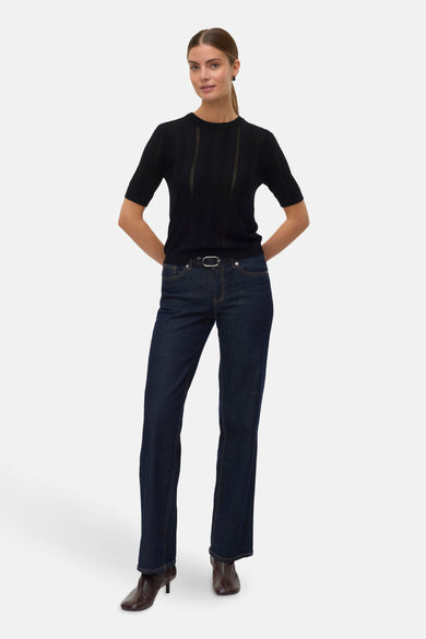 Zwarte rondehals trui van VERO MODA gedragen met een high-waist jeans en enkellaarsjes.
