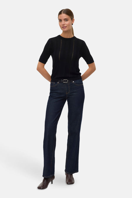 Zwarte rondehals trui van VERO MODA gedragen met een high-waist jeans en enkellaarsjes.