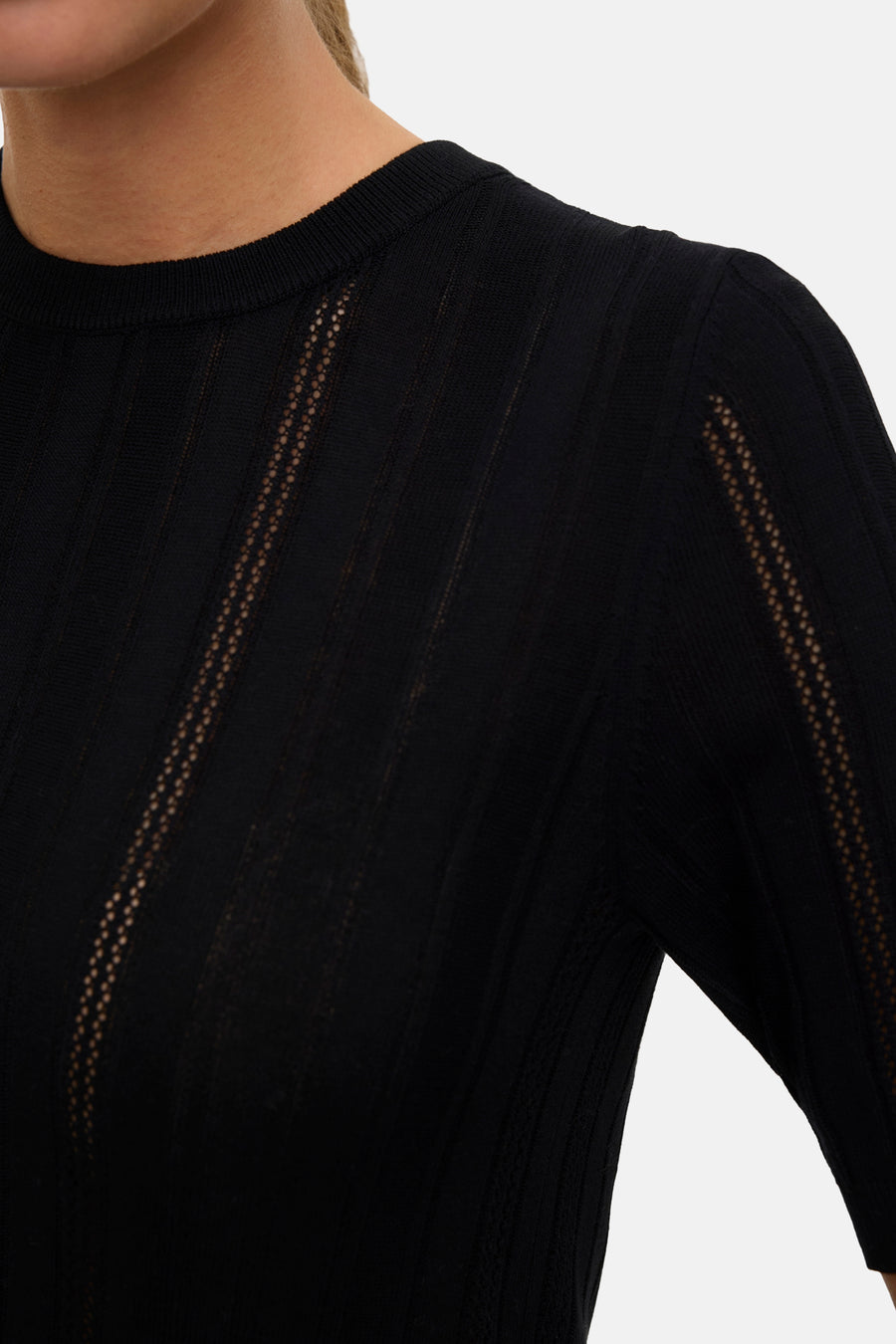 Pull noir à col rond de VERO MODA, avec motif ajouré sur la poitrine et les manches.