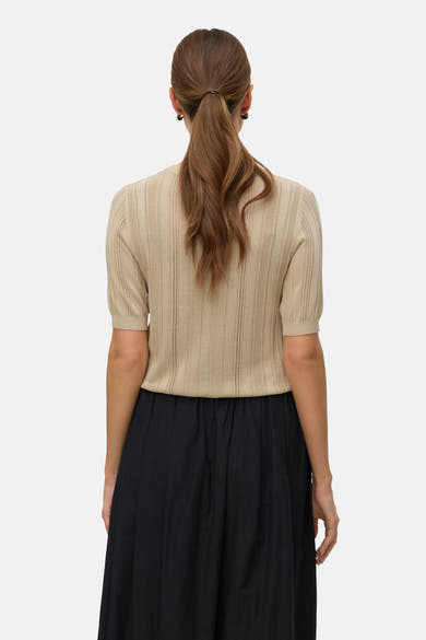 Pull à col rond vert de VERO MODA, avec une texture tricotée et des manches courtes, porté avec une jupe noire.
