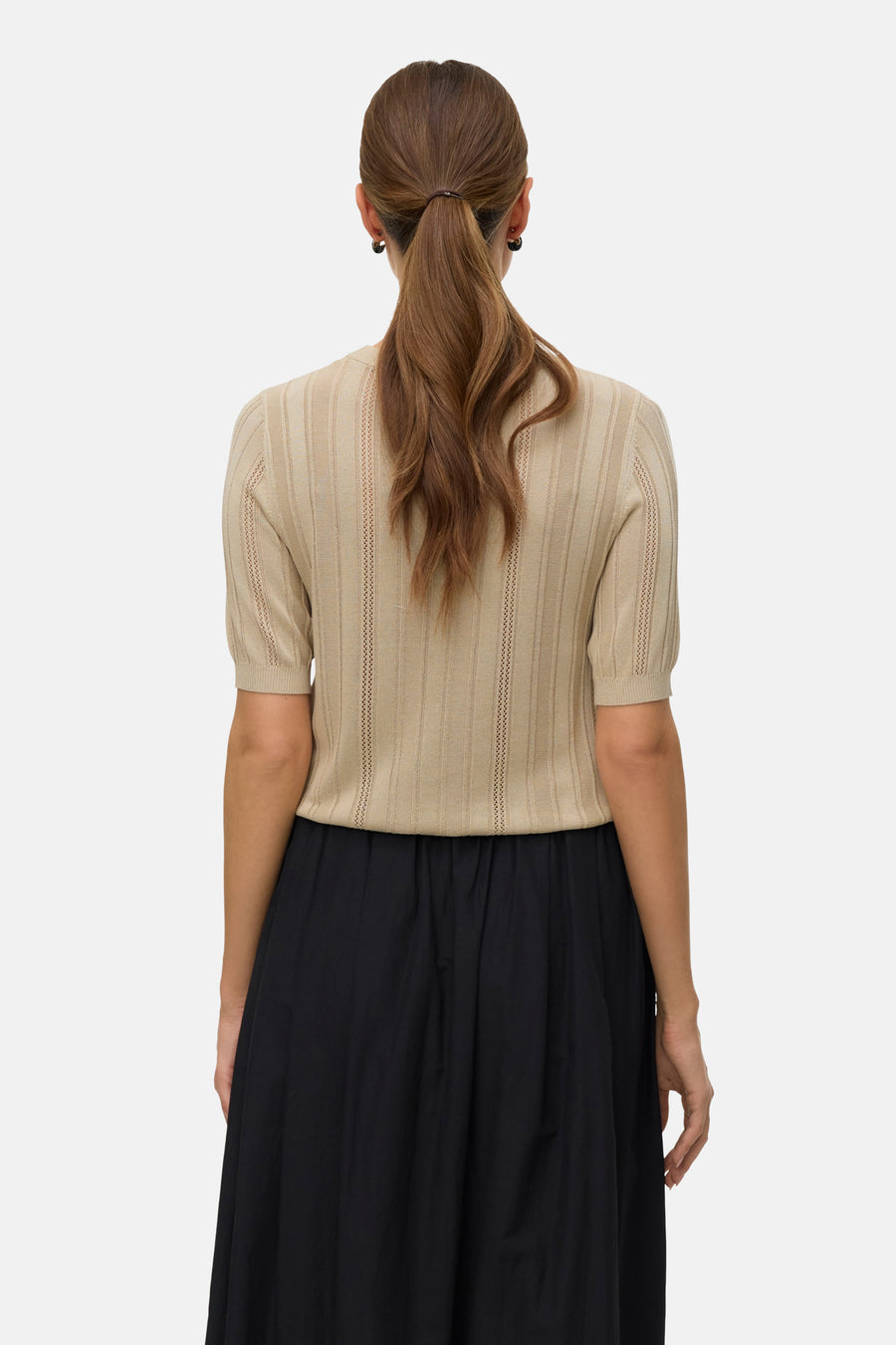 Pull à col rond vert de VERO MODA, avec une texture tricotée et des manches courtes, porté avec une jupe noire.
