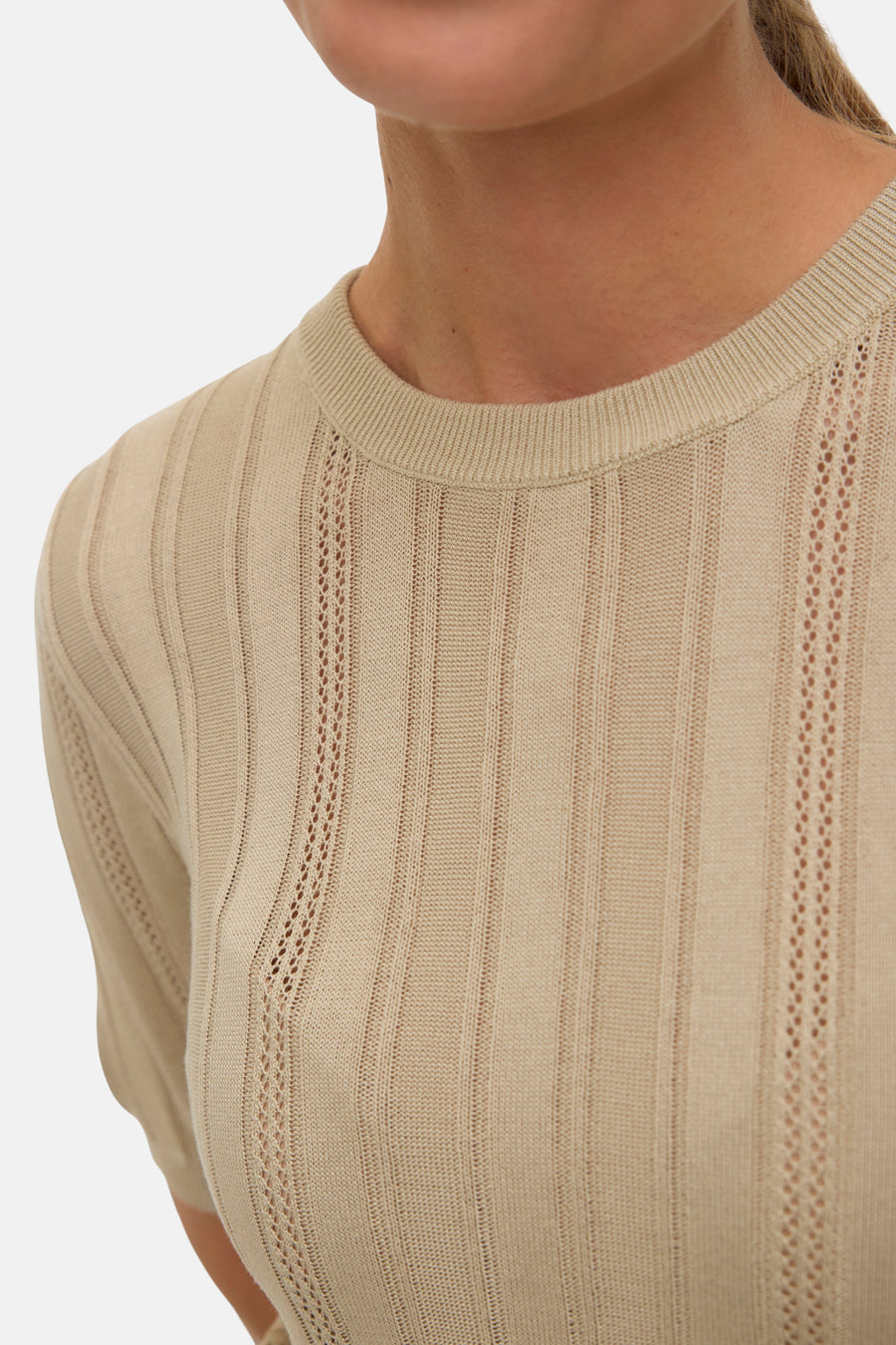 Pull à col rond beige de VERO MODA, avec des motifs ajourés verticaux sur le devant.