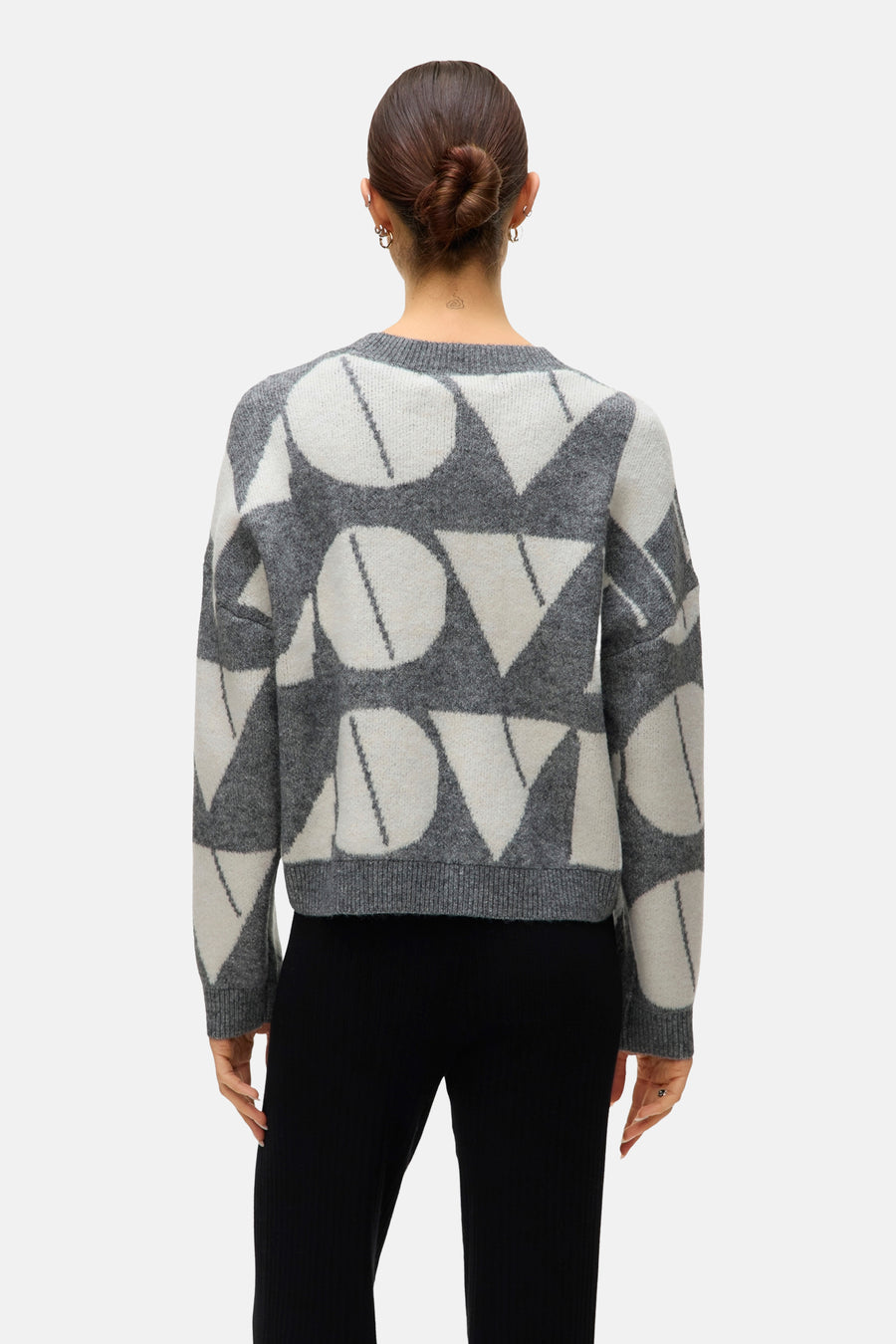 Grijze trui met ronde hals van VERO MODA, met contrasterend geometrisch patroon, gedragen met een zwarte broek.