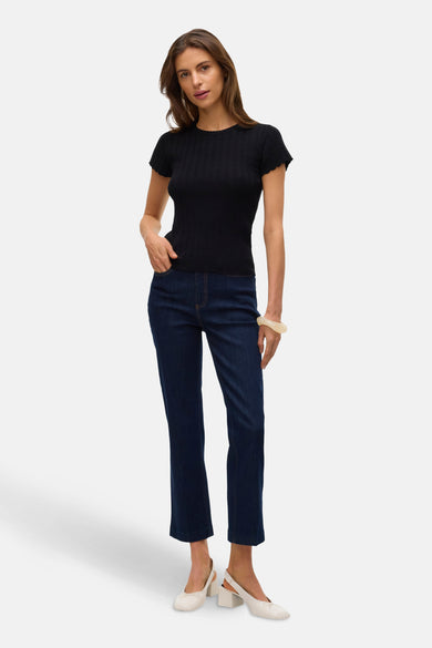 Zwart T-shirt met korte mouwen van VERO MODA, gedragen met een blauwe jeans en witte schoenen.
