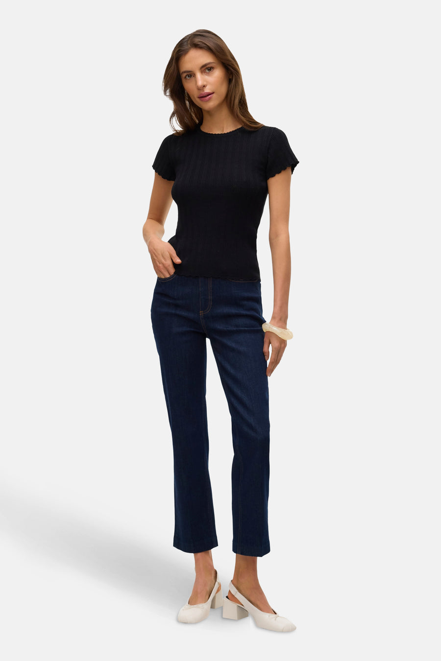 T-shirt noir à manches courtes de VERO MODA, porté avec un jean bleu et des chaussures blanches.