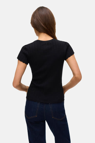 T-shirt noir à manches courtes de VERO MODA, côtelé avec ourlet festonné, porté avec un jean bleu foncé.