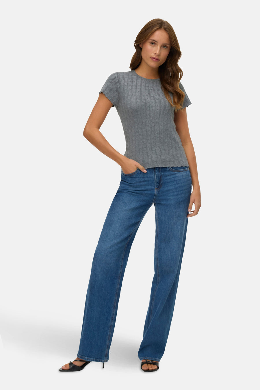 Grijs T-shirt met korte mouwen van VERO MODA, gedragen met een wijde blauwe jeans en zwarte hoge hakken.