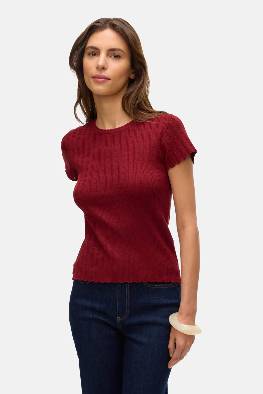 T-shirt rouge à manches courtes de VERO MODA® avec texture côtelée et ourlet festonné, porté avec un jean.