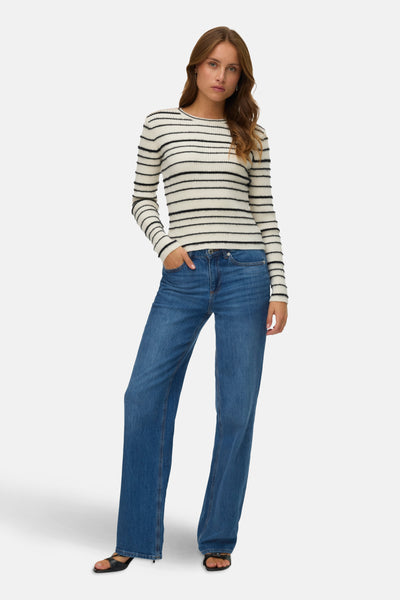 Pull à col rond blanc à rayures noires de VERO MODA®, porté avec un jean bleu ample.