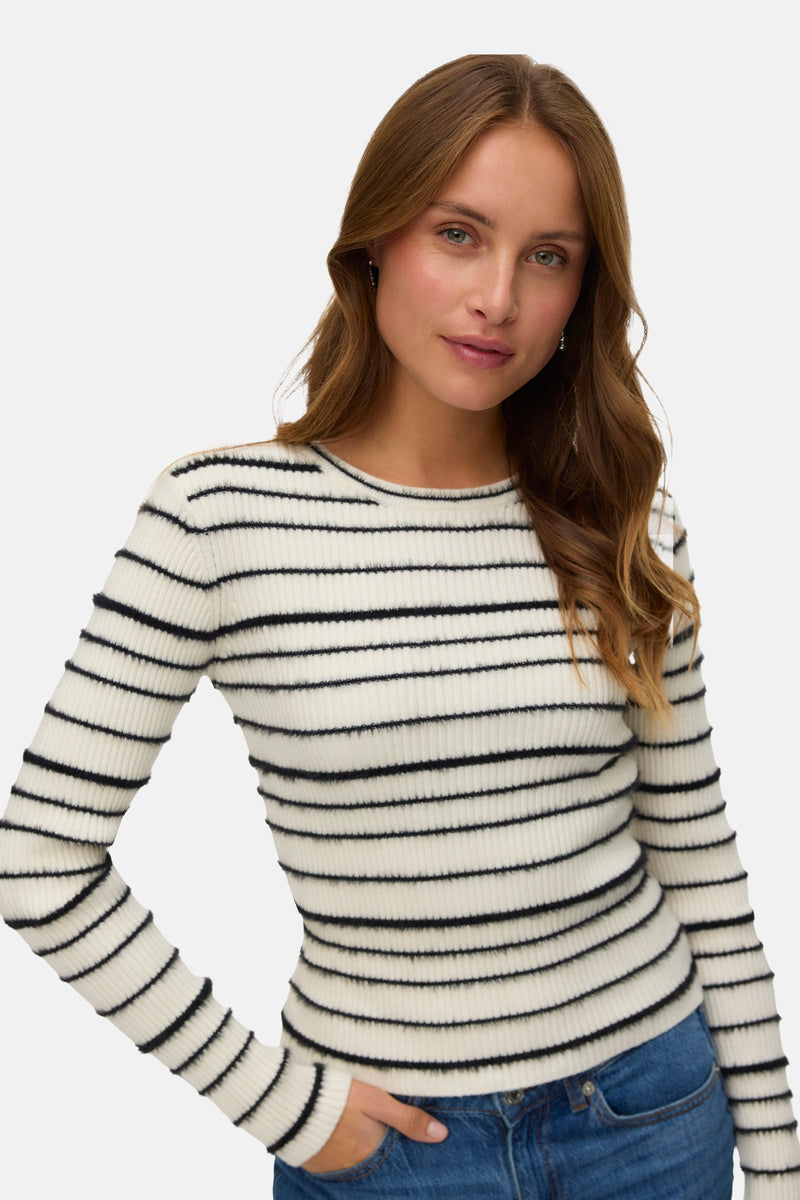 Pull à col rond blanc de VERO MODA avec motif à rayures horizontales, porté avec un jean bleu.