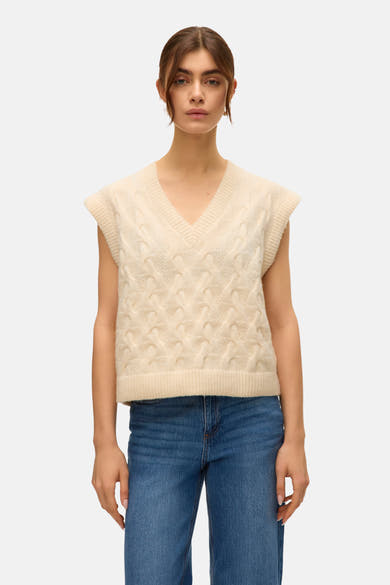 Débardeur beige de VERO MODA, avec un motif à torsades, porté avec un jean bleu.

