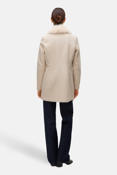 Ecru korte jas van VERO MODA®, met imitatiebontkraag, gedragen met een donkerblauwe jeans.
