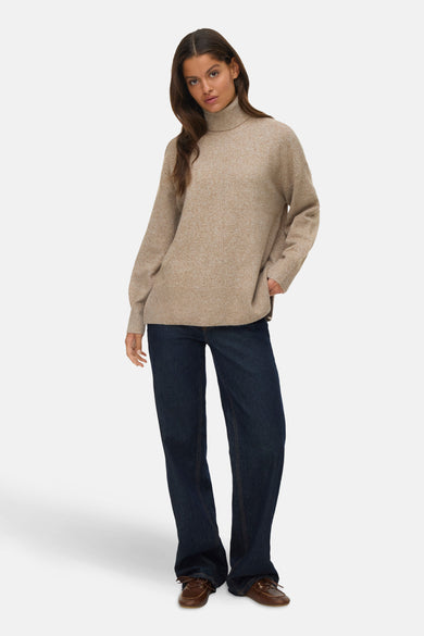 Pull à col roulé beige de VERO MODA®, porté avec un jean foncé et des chaussures bateau marron.

