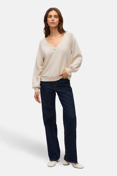 Beige sweater van VERO MODA®, gedragen met een donkerblauwe jeans en witte schoenen.