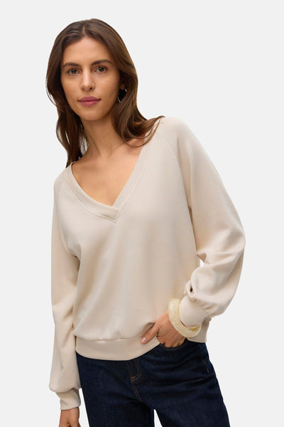 Sweat-shirt beige de VERO MODA, porté avec un jean bleu foncé et un bracelet épais couleur crème.
