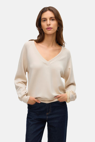 Beige sweatshirt van VERO MODA, gedragen met een donkerblauwe jeans, lange mouwen en geplooide manchetten.