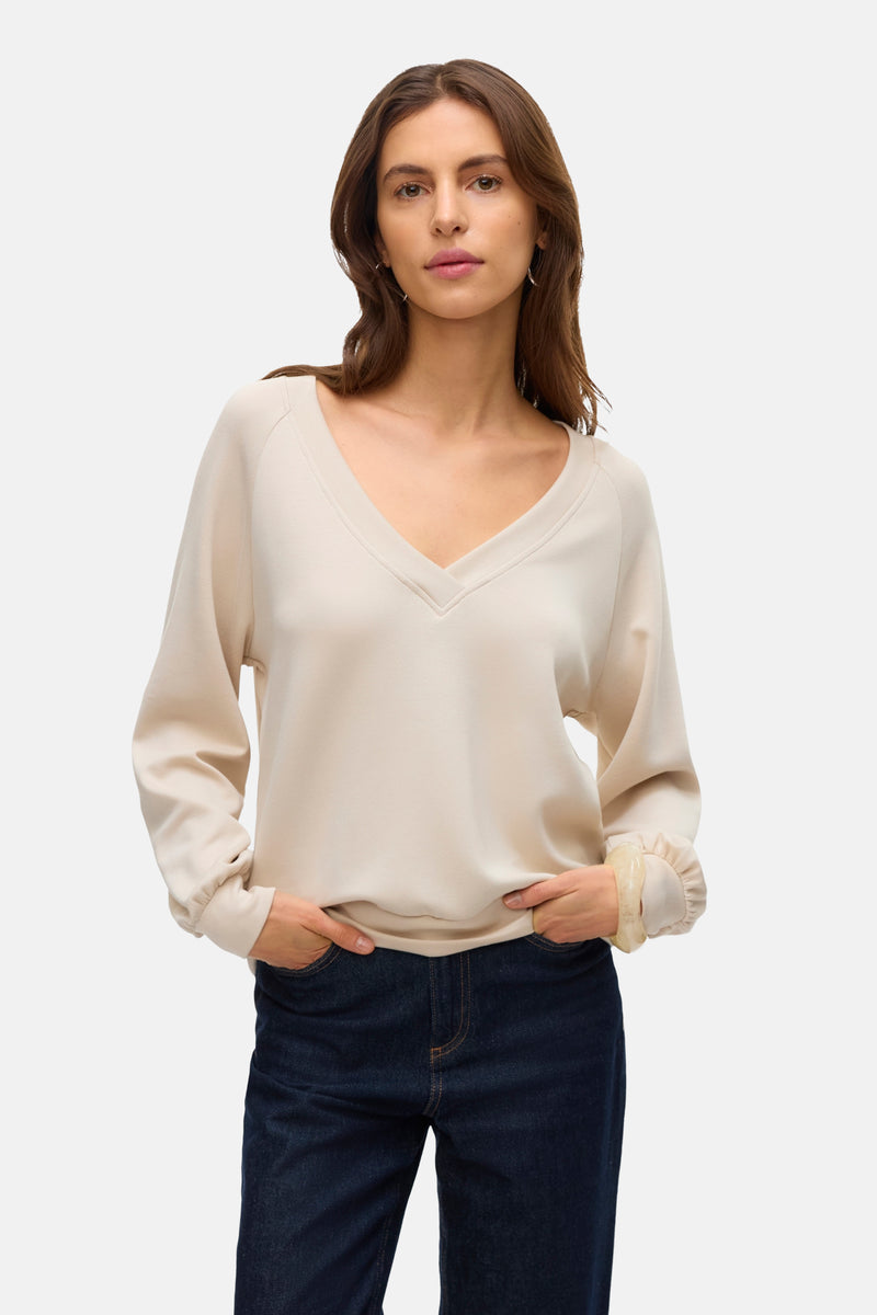 Beige sweatshirt van VERO MODA, gedragen met een donkerblauwe jeans, lange mouwen en geplooide manchetten.