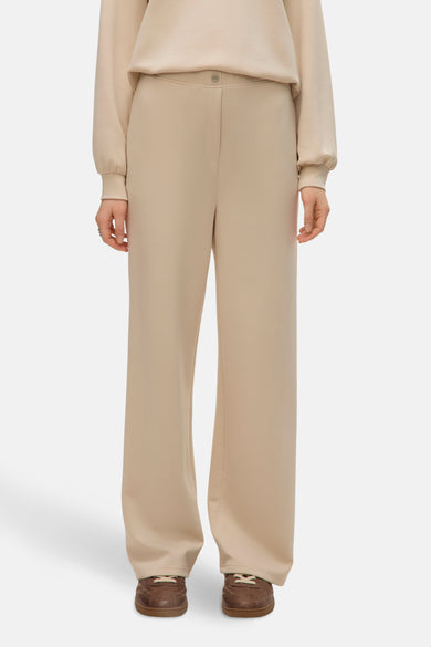 Pantalon écru de VERO MODA, coupe ample avec bouton, porté avec un sweat-shirt beige et des chaussures marron.