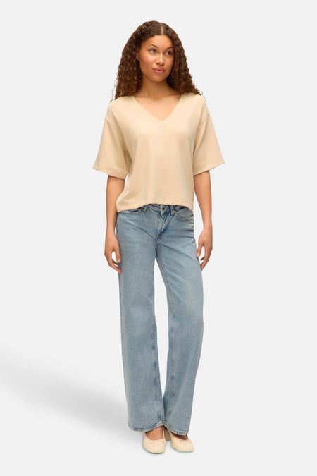 Ecru T-shirt met korte mouwen van Vero Moda, gedragen met een wijde jeans en ballerina's.