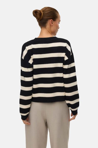 Cardigan rayé noir et blanc de Vero Moda, porté avec un pantalon beige, vue de dos.