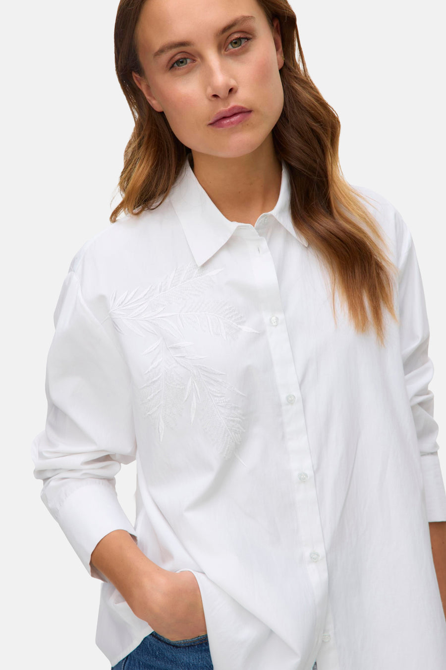 Wit overhemd met lange mouwen van VERO MODA versierd met bloemenborduursels aan de voorkant, gedragen met een spijkerbroek.