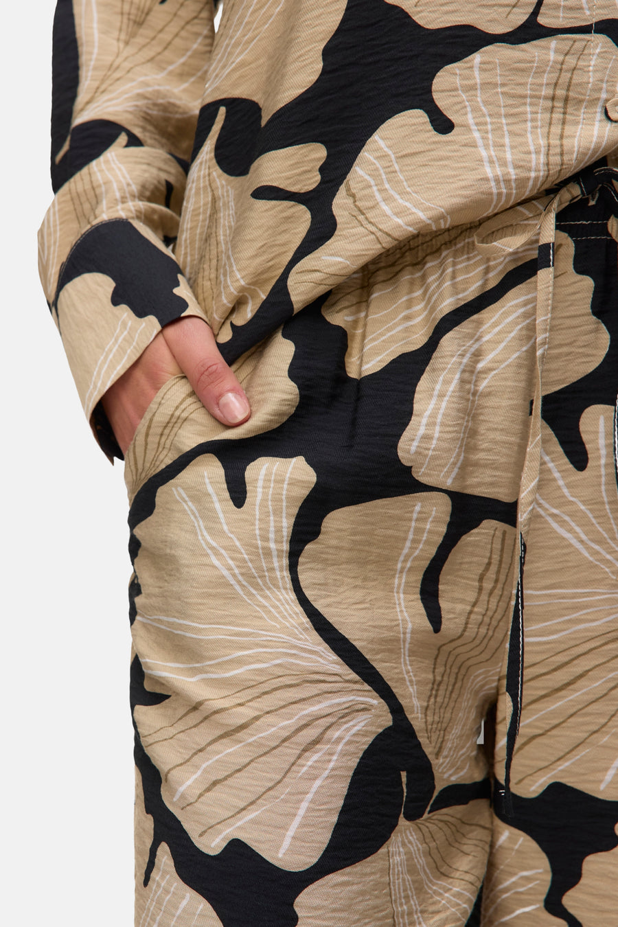 Multikleurige broek van VERO MODA® met abstract bloemenpatroon in beige, zwart en wit, hand in zak.
