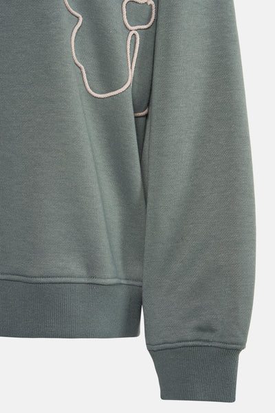 Groene trui van VERO MODA met ecru koordapplicatie en mesh-textuur.
