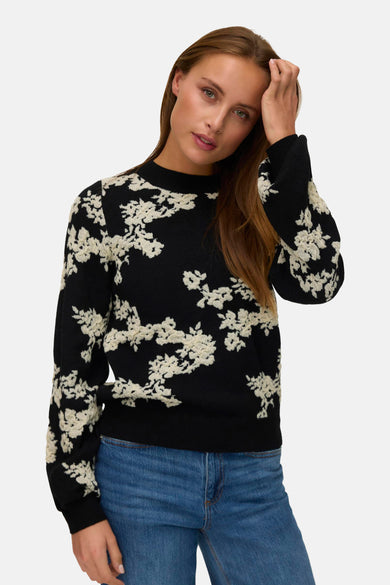 Pull à col rond noir de VERO MODA® avec motif floral en relief porté avec un jean bleu.
