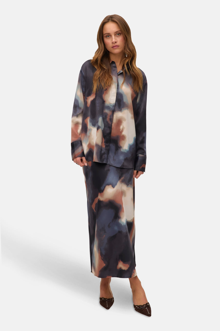 Multikleuren blouse met lange mouwen van VERO MODA® met abstracte print, gedragen met een bijpassende rok en bruine schoenen.