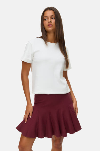 Korte bordeauxrode rok van VERO MODA®, met plooien en gedragen met een effen wit T-shirt.