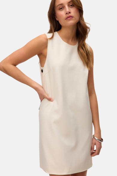 Beige jurk van VERO MODA® met knoopdetails op de schouder en een zilveren armband om de pols.