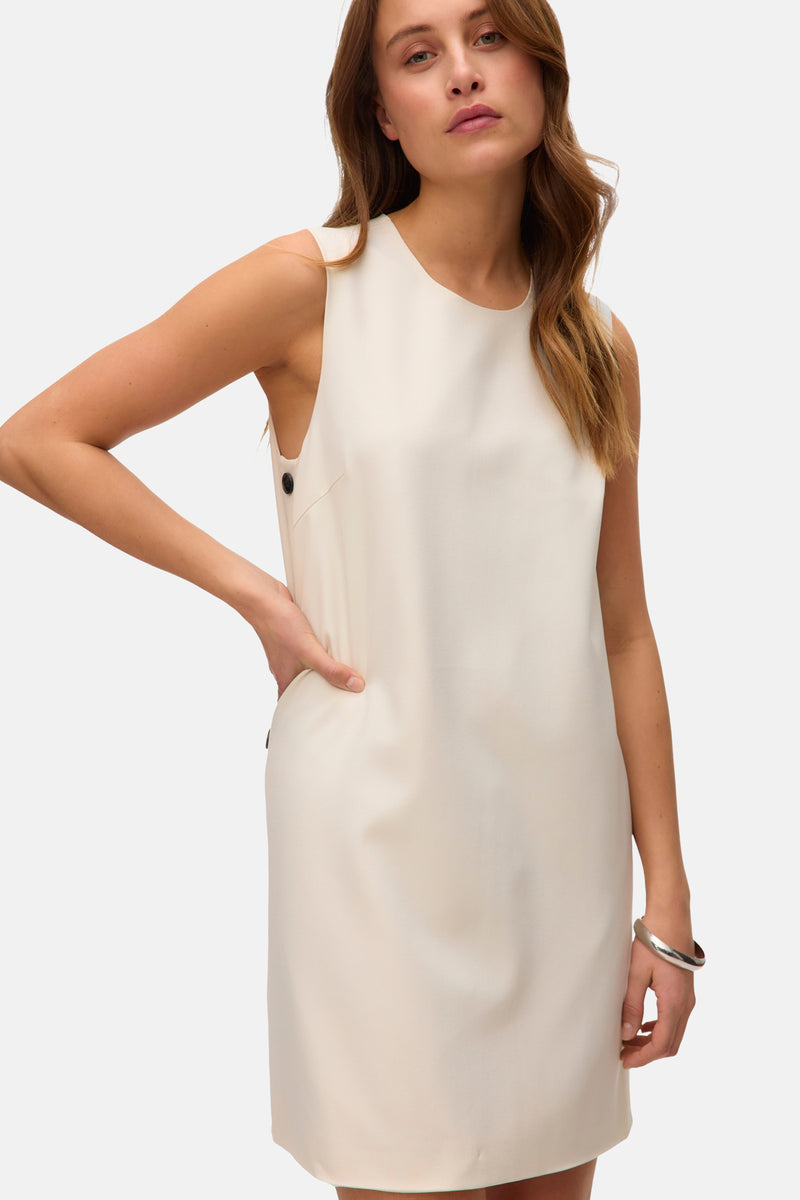 Beige jurk van VERO MODA® met knoopdetails op de schouder en een zilveren armband om de pols.