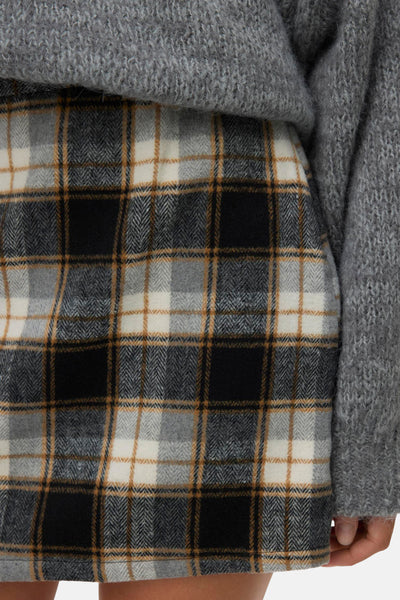 Jupe courte à carreaux multicolores de VERO MODA, motif à chevrons avec pull gris texturé visible.