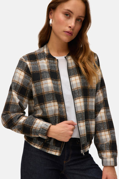 Kort geruit jack met meerdere kleuren van VERO MODA, met ritssluiting en gedragen over een wit T-shirt en een donkere jeans.