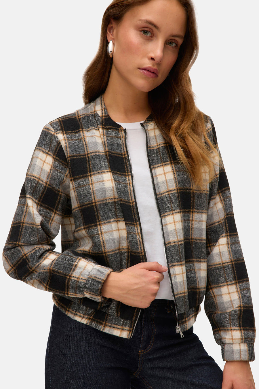 Kort geruit jack met meerdere kleuren van VERO MODA, met ritssluiting en gedragen over een wit T-shirt en een donkere jeans.