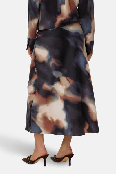 Multikleurige lange rok van VERO MODA met abstract patroon, tot aan de enkels vallend, gedragen met bruine pumps.
